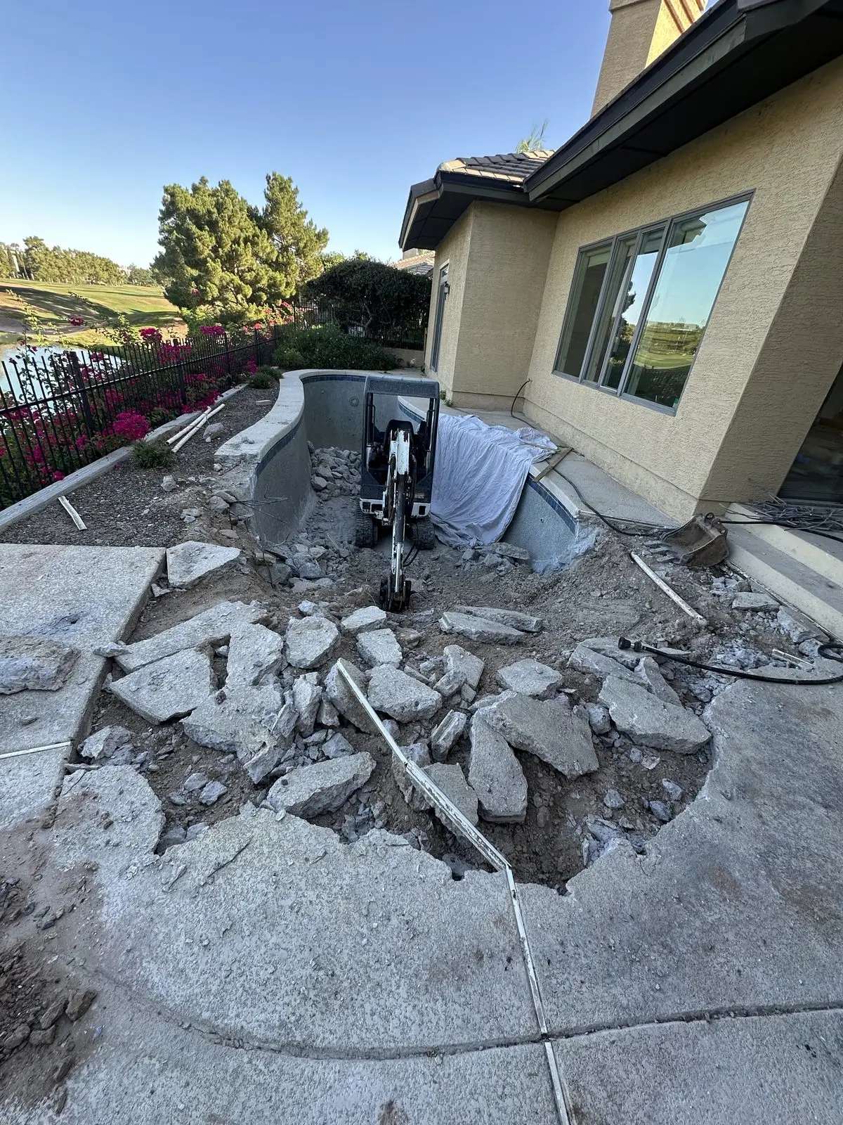 Pool deck torn out with a mini excavator because the pool needs a remodel